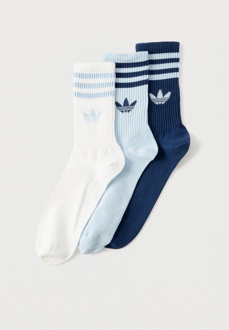 Három Adidas zokni, fehér, világoskék és sötétkék színben, mindegyiken két csík és a tetejénél a trefoil logó található.