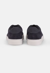 Dark navy suede sneakers with a white rubber sole. Rounded back with a smooth accent panel. Low-top design, minimal lacing.