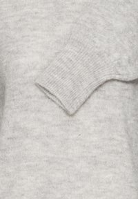 Puha világosszürke kötött pul�óver, hajtott ujjakkal, ribbelt mandzsetta textúrával és finom gyapjú anyag részletekkel.