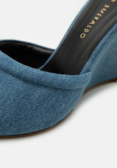 Pantofii wedge din denim de culoare albastră, având un exterior din material texturat cu un design curbat și căptușeală interioară neagră. Se remarcă prin toc ușor înălțat.