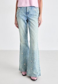 Lichtblauwe flared jeans van denim, voorzien van bloemenborduursels langs de zijkanten, met een licht vervaagde afwerking en zichtbare stikseldetails.