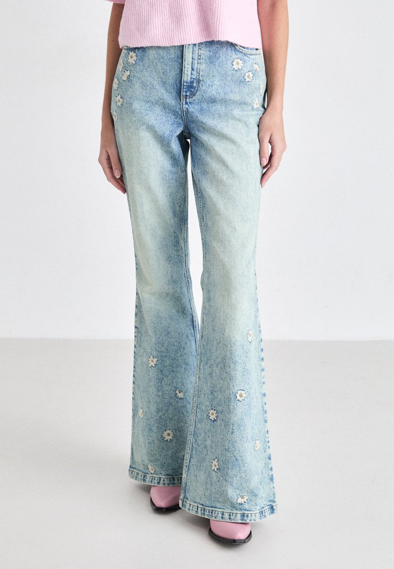 Lichtblauwe flared jeans van denim, voorzien van bloemenborduursels langs de zijkanten, met een licht vervaagde afwerking en zichtbare stikseldetails.