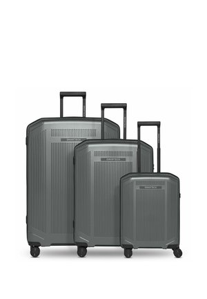 Tre valigie rigide grigie di diverse dimensioni con maniglie nere estese e quattro ruote spinner, con il marchio "SMARTBOX" sul davanti.