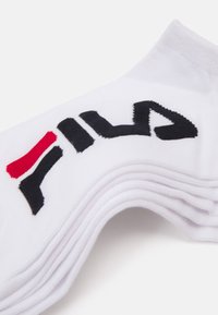Calcetines de algodón blancos con un logo de Fila en negro y rojo. Los calcetines tienen una textura acanalada y un diseño clásico de longitud media.