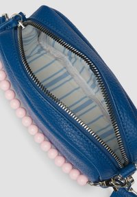 Blauwe leren tas met een ritssluiting en roze kraalaccenten. Interieur heeft een gestreept patroon op een lichte achtergrond.