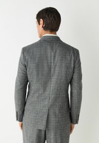 Grijs geruit colbert met een enkele split aan de achterkant, getailleerde pasvorm en knoopmanchetten, gecombineerd met bijpassende broek.