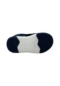 Sole di sneakers navy e bianco con gomma testurizzata, dotata di fori di ventilazione e un logo circolare. Punta arrotondata e dettagli a contrasto.