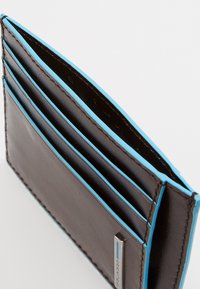 Tarjetero de cuero marrón con costuras de acento azul, que cuenta con múltiples ranuras para tarjetas y un detalle de hardware plateado.