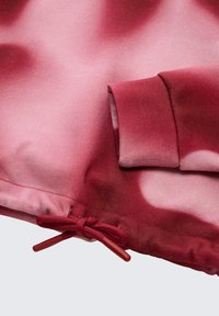 Pullover in diverse tonalità di bordeaux e rosa, con una texture liscia, polsini elasticizzati e cordino regolabile all'orlo.