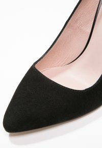 Chaussure à talon haut en daim noir à bout pointu avec une doublure intérieure en cuir lisse rose clair.