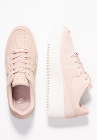 Sneakers Nike Air Force 1 in camoscio rosa con tomaia testurizzata, lacci piatti, fori di aerazione sulla punta e suola in gomma bianca.