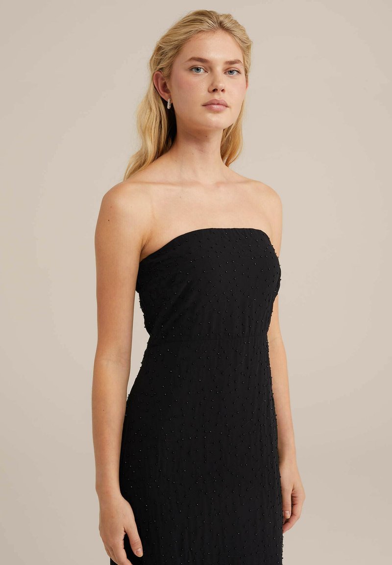 Vestido negro sin mangas, hecho de una tela texturizada con puntos en relieve, con un cuerpo ajustado y un diseño de falda recta. Silueta simple y elegante.