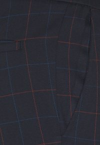 Marine stof met een diagonale weving, voorzien van een geruit patroon in rood en blauw. De textuur lijkt glad en gestructureerd.