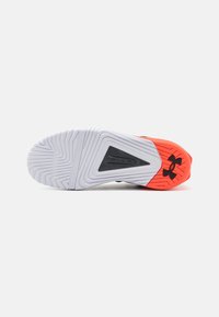 Sort og orange atletiske sko sål med en tekstureret hvid ydersål, der har riller og en sort trekantet accent med branding.