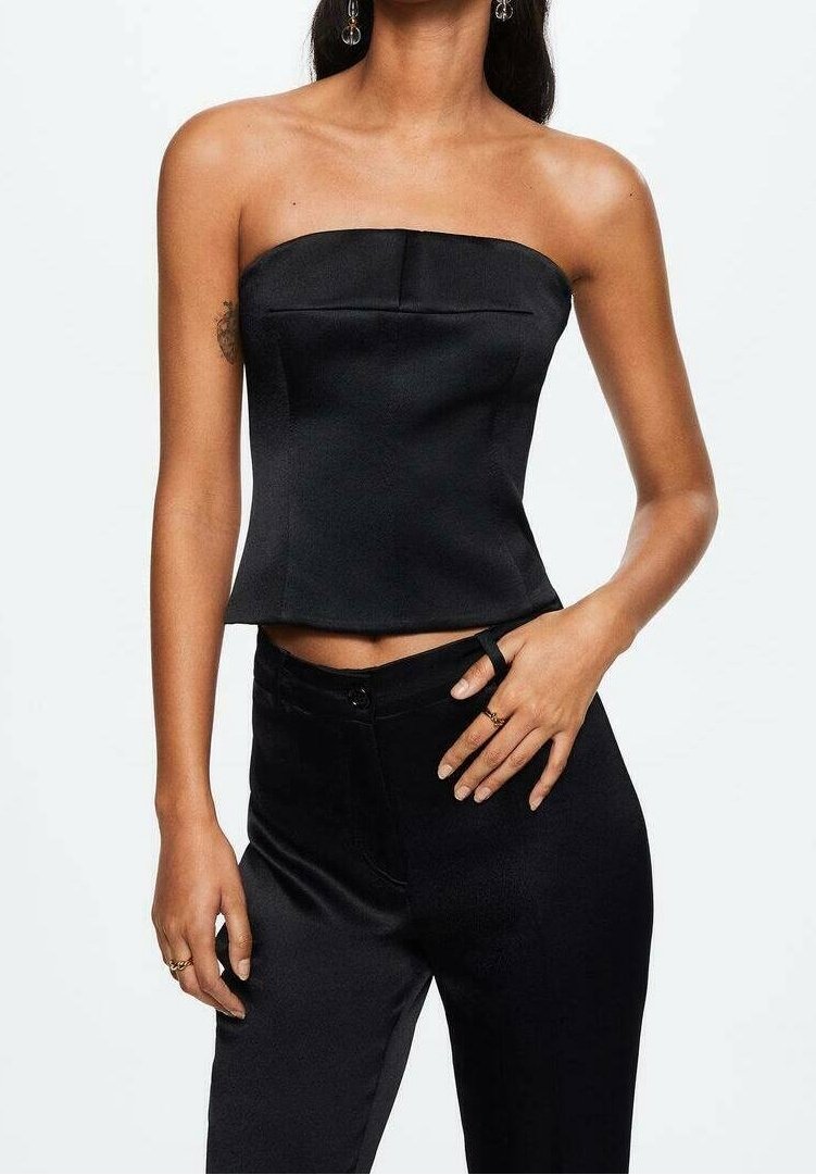 Top nero senza spalline con un corpetto strutturato, caratterizzato da una consistenza liscia in satin e una lunghezza cropped, abbinato a pantaloni neri aderenti.