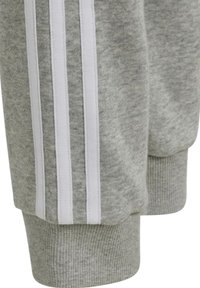 Graue Sweatpants mit weißen vertikalen Streifen an den Seiten, gerippten Bündchen und einem weichen, strukturierten Stoff.