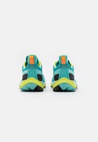 Scarpe da corsa blu e giallo neon con un accento nero. Presentano una suola imbottita e un marchio ben visibile sul tallone e sui lati.