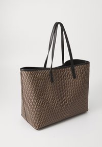 Brown patterned tote bag with black leather handles. Features a geometric design and a structured shape. Open top, no visible hardware.