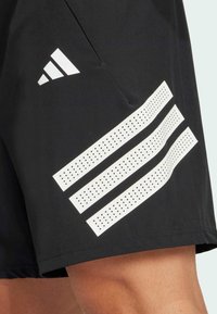 Schwarze Sportshorts mit einem weißen drei-streifen Design. Verfügt über eine Seitentasche und einen glatten, leichten Stoff.