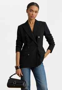 Διπλής όψης μαύρο σακάκι με μπαλαντέρ, που διαθέτει δύο μπροστά τσέπες και κουμπιά. Συνδυάζεται με τζιν μέτριας πλύσης και μαύρη τσάντα.