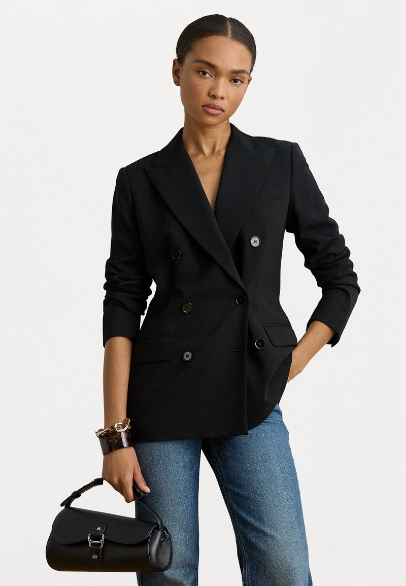 Διπλής όψης μαύρο σακάκι με μπαλαντέρ, που διαθέτει δύο μπροστά τσέπες και κουμπιά. Συνδυάζεται με τζιν μέτριας πλύσης και μαύρη τσάντα.