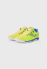 Limegrønne trening sneakers med blå detaljer, som har en teksturert overdel, hvit gummisåle og kontrasterende svart snøresystem.
