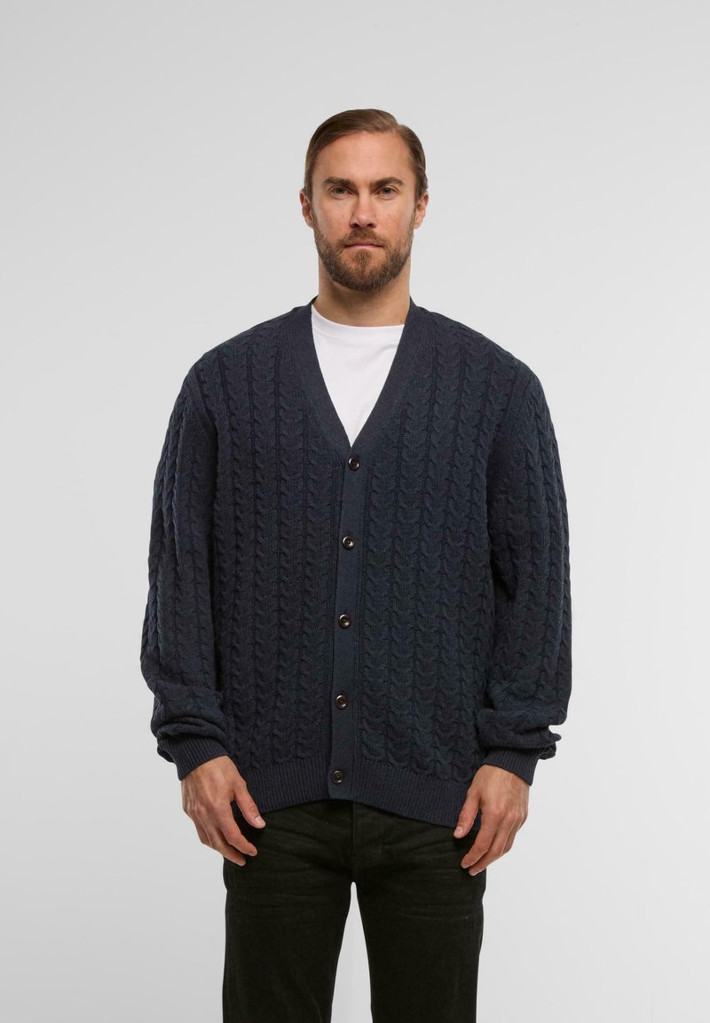 Gilet en tricot bleu marine avec un motif en torsades, col en V et fermeture à boutons. Présente des poignets et un ourlet côtelés pour un bon ajustement.