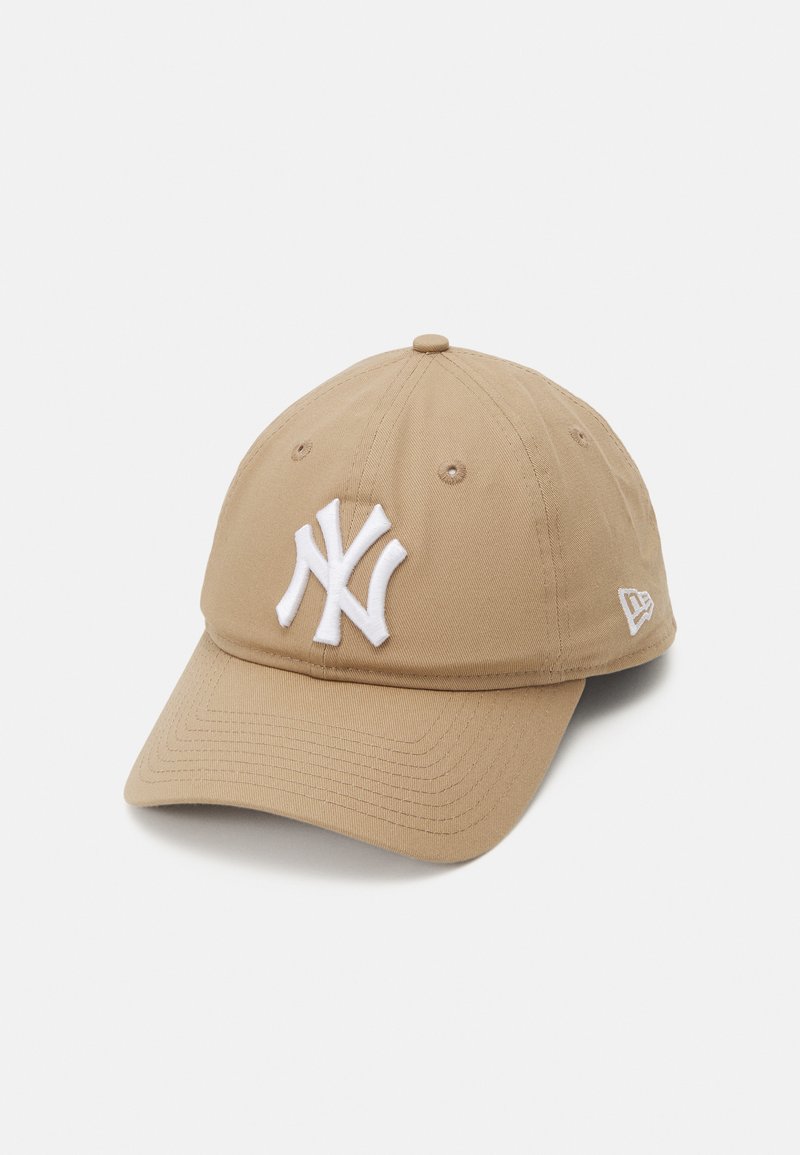 Khaki színű baseball sapka, elöl fehér hímzett New York Yankees logóval, ívelt ernyővel és szellőzőlyukakkal a tetején.