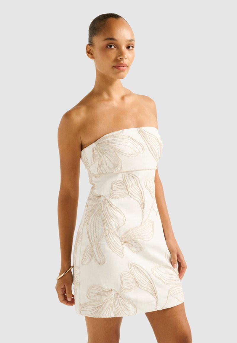 Trägerloses weißes Kleid mit beigem Blumenstickerei, eng anliegendem Oberteil und A-Linien-Rock. Glattes Material mit leichtem Glanz und minimalen Details.