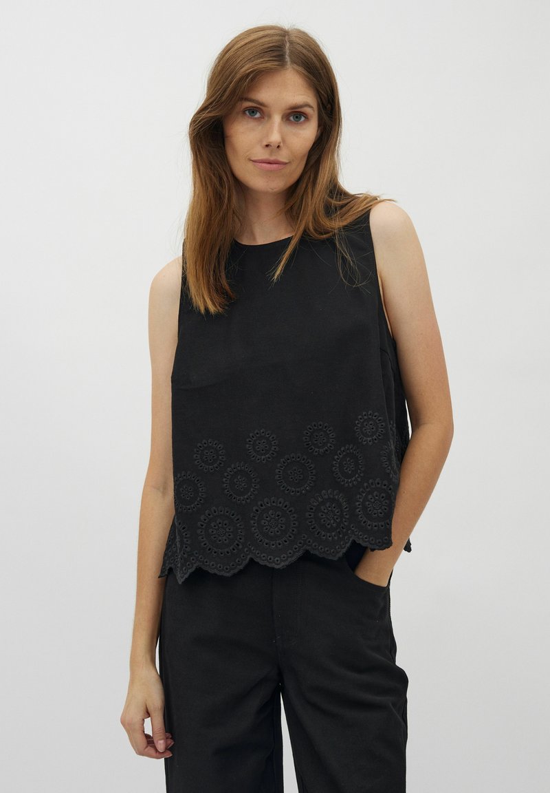 Zwarte mouwloze top met een scalloped zoom en cirkelvormige borduursels. Gemaakt van een textiel met een eenvoudige, strakke ontwerp.