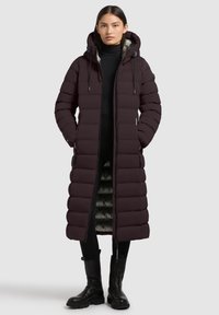 Long, puffer coat in deep burgundy, featuring a hood, zipper closure, and two side pockets. The interior showcases a contrasting gray lining.