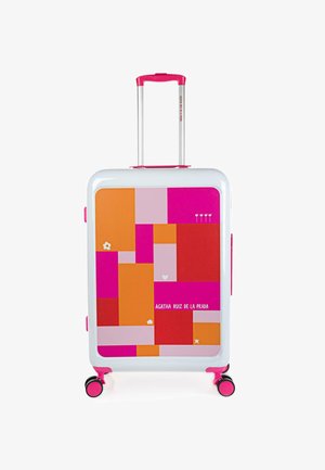 Maleta rígida con base blanca, que presenta un colorido patrón geométrico con acentos en rosa, naranja y rojo. Ruedas dobles y mango telescópico.