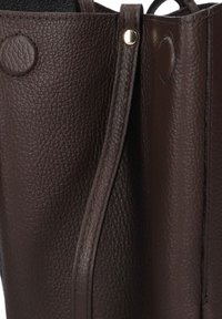 Bruine leren handtas met een getextureerd oppervlak, voorzien van een gouden drukknoop en een elegante, gebogen vorm.