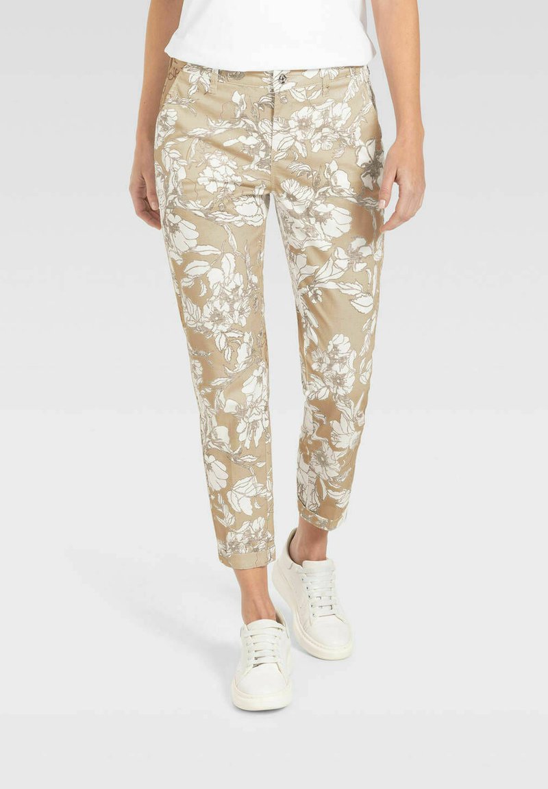 Blumengemusterte, beige Hose mit schlankem Schnitt und knöchellang, kombiniert mit weißen Sneakers, aus weichem, glattem Stoff.