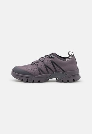 Purple athletic shoes with a mesh upper, rubber sole, and streamlined design. Features elastic laces and textured accents on the sides.