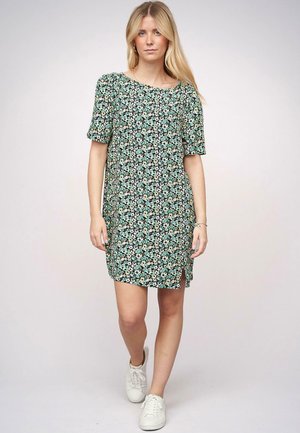 Blumenkleid mit kurzen Ärmeln, das einen schwarzen Hintergrund und grüne, gelbe sowie weiße Blumenmuster aufweist. Mit seitlichen Schlitzen und lockerer Passform.