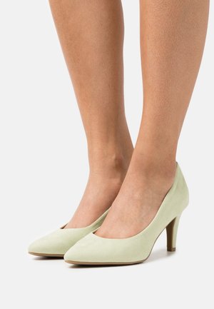 Escarpins hauts en daim vert avec un bout pointu et un talon fin, présentant une texture lisse et un design minimaliste.