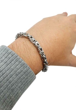 Braccialetto in metallo argentato con design a catena. I link sono texturizzati e alternano forma, indossato su un polso con un maglione grigio.