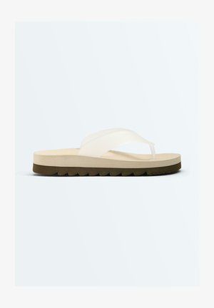 Single beige flip-flop with thick sole and white strap, shown in side view on a plain light gray background.