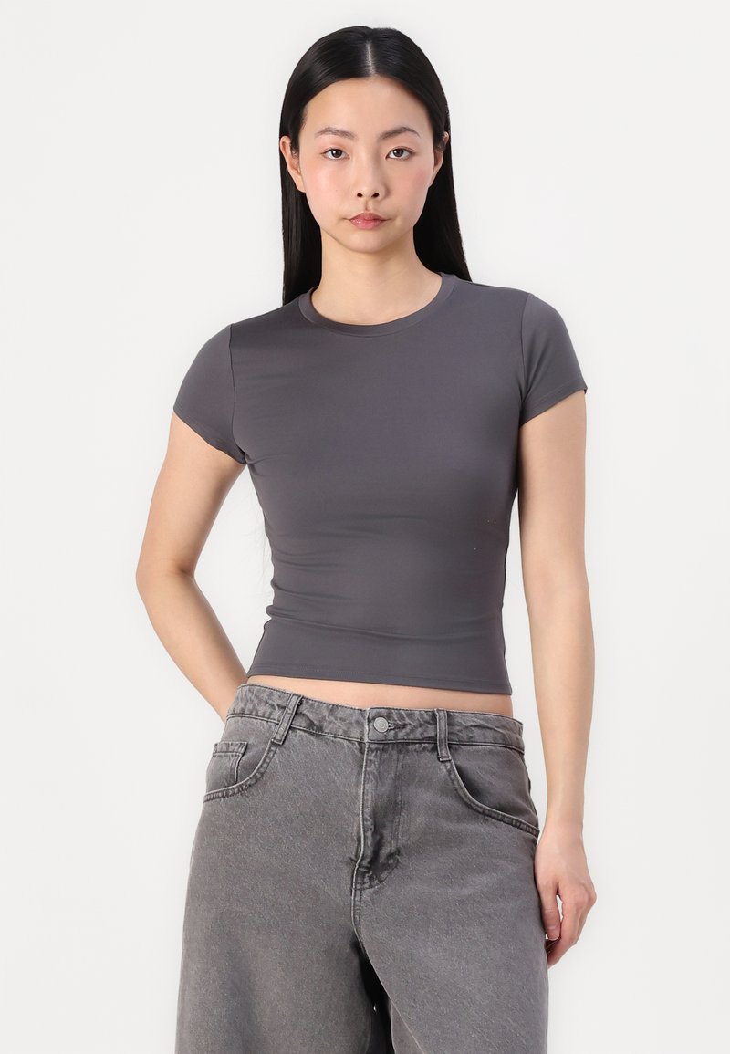 Graues, eng anliegendes T-Shirt mit kurzen Ärmeln, Rundhalsausschnitt und glatter Textur, kombiniert mit hoch taillierten grauen Jeans aus Denim.