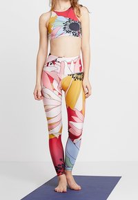 Ensemble de brassière de sport et de leggings à motifs floraux ; couleurs vives comprenant du rose, du jaune et du bleu ; matériau extensible ; design ajusté.