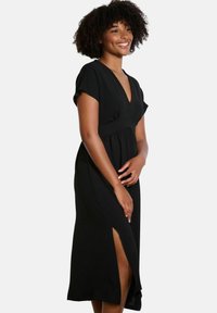 Black midi dress with short sleeves, v-neckline, and a cinched waist. Features a side slit and soft, textured fabric for comfort.