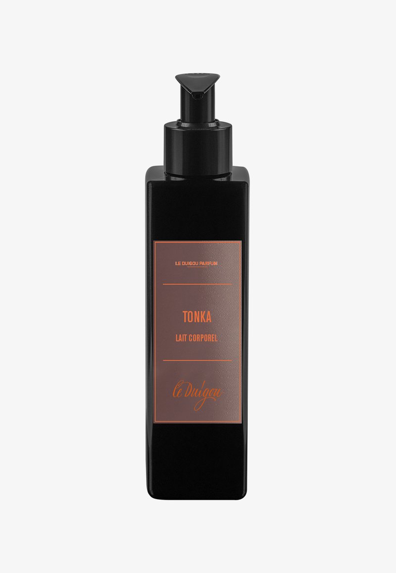 Bouteille rectangulaire noire avec un bouchon-pompe, ornée d'une étiquette marron sur laquelle est inscrit "TONKA LAIT CORPOREL" en lettres orange. Design simple et épuré.