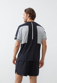 Herren Sportoberteil mit einem Farbblockdesign in Dunkelblau und Hellgrau, kurzen Ärmeln und einem reflektierenden Rückendetail.