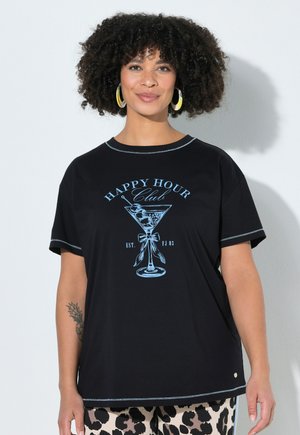 Vrouw met krullend haar, gouden oorringen in hoepelvorm en een zwart T-shirt met een blauwe martiniglas en de tekst "Happy Hour Club".