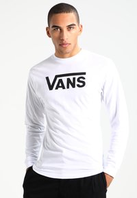 Valkoinen pitkähihaisten paita, joka on tehty puuvillasekoitteesta ja jossa on hyvin näkyvä musta "VANS"-logo rintamalla. Sileä rakenne ja rento istuvuus.