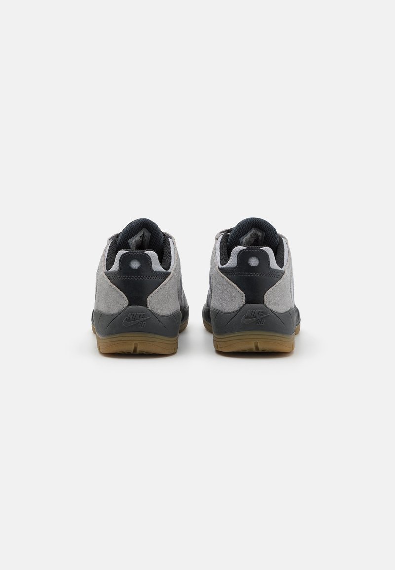 Graue Wildledersneaker mit schwarzen Akzenten und Sohle aus Gummi. Verfügt über einen gepolsterten Kragen und ein Logo an der Ferse. Rückansicht sichtbar.