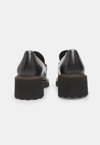 Scarpe nere in pelle con tacco appuntito e suola spessa in gomma. Presentano dettagli delle cuciture e un leggero rialzo al tacco.