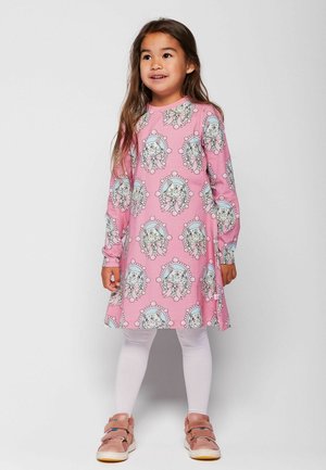 Hosszú ujjú rózsaszín ruha, amely ismétlődő mintázatként ábrázolt állatokat tartalmaz kör alakú keretekben, fehér leggingsszel és rózsaszín cipővel párosítva.