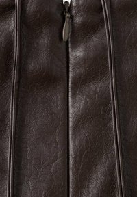 Chaqueta marrón de cuero sintético con textura visible, cremallera central y costuras verticales. Acabado suave con ligero brillo y arrugas.